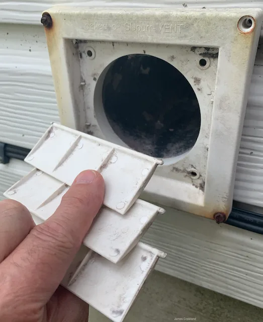 Exterior dryer vent outlet with three hinged plastic flaps that close between drying cycles