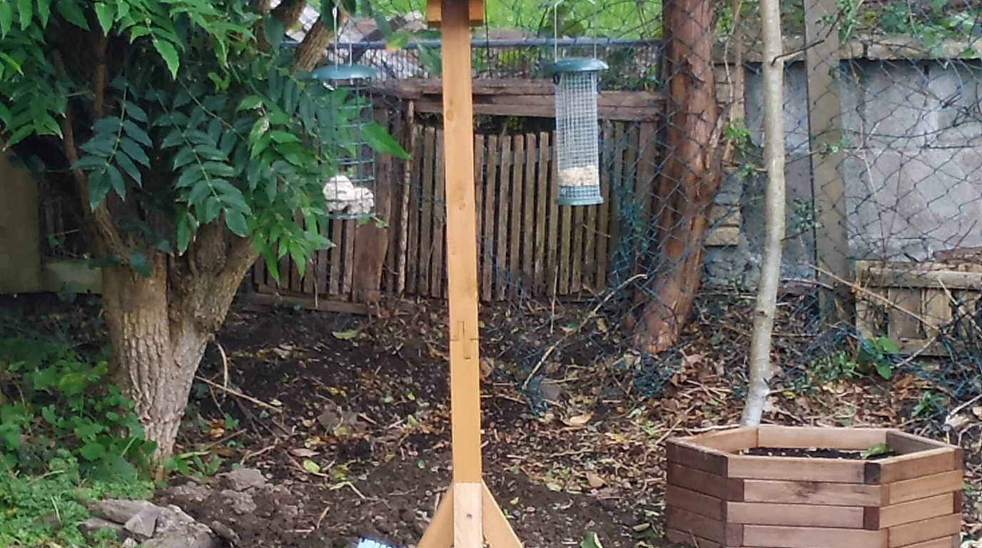A tube bird feeder placed in a private garden